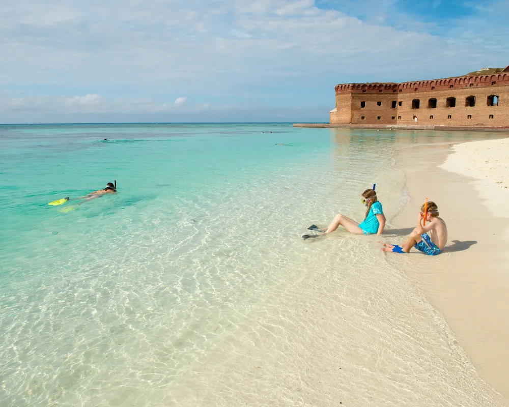 children snorkeling the shoreline at the Dry Tortugas with crystal clear blue watersu